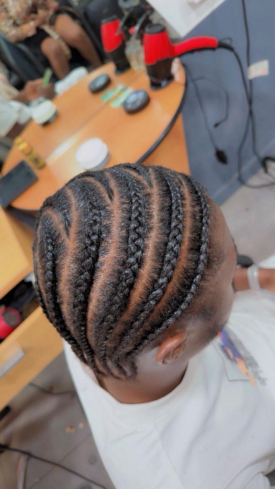 Nattes collées régulières sur cheveux naturels d’un enfant, vues du dessus.