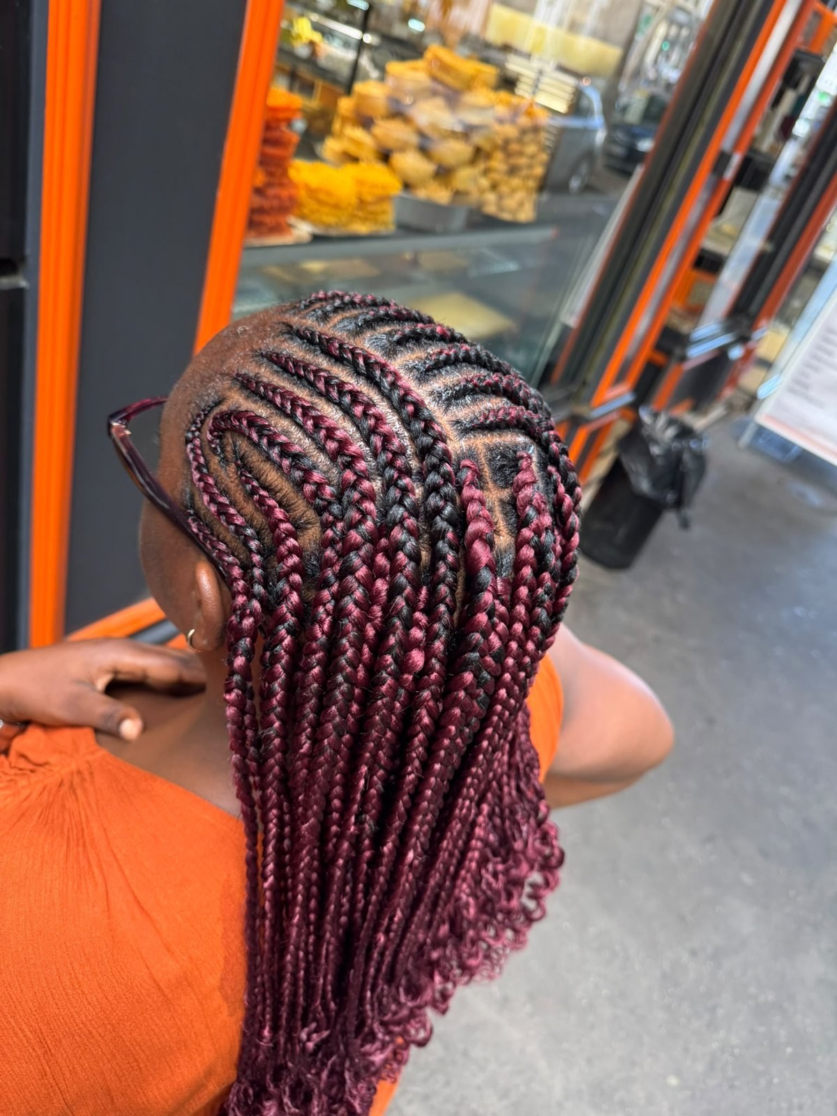 Nattes collées noires et bordeaux prolongées par des tresses, vues de dos.