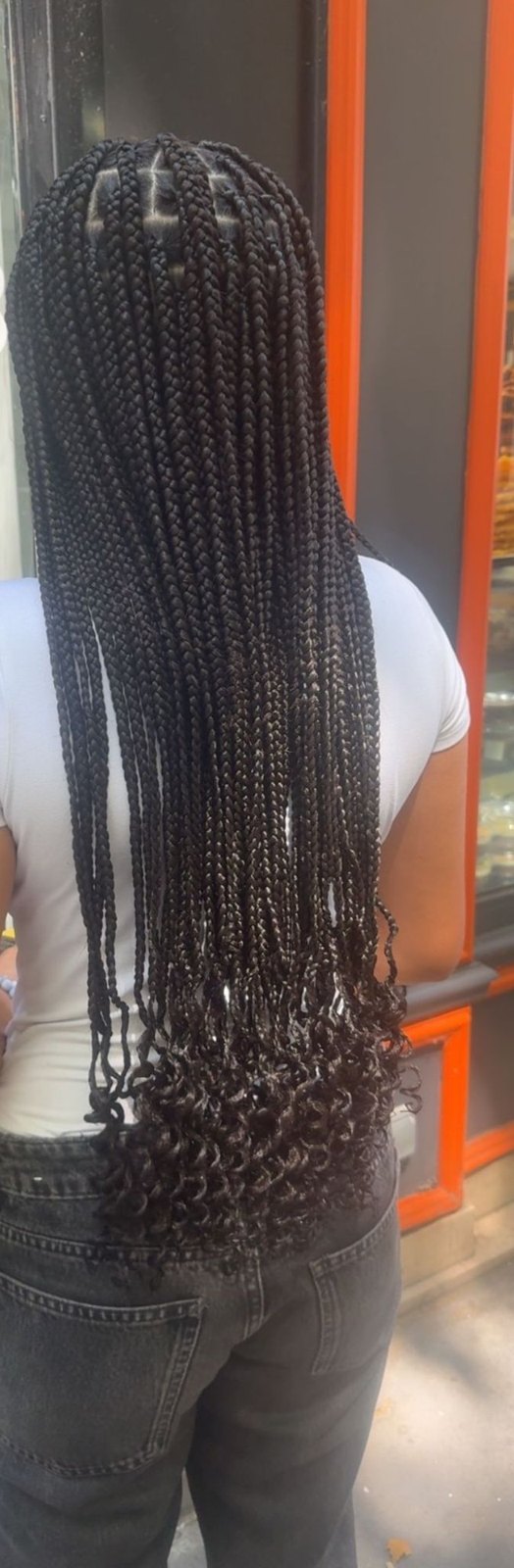 Longues knotless braids brun foncé aux pointes bouclées, vues de dos.
