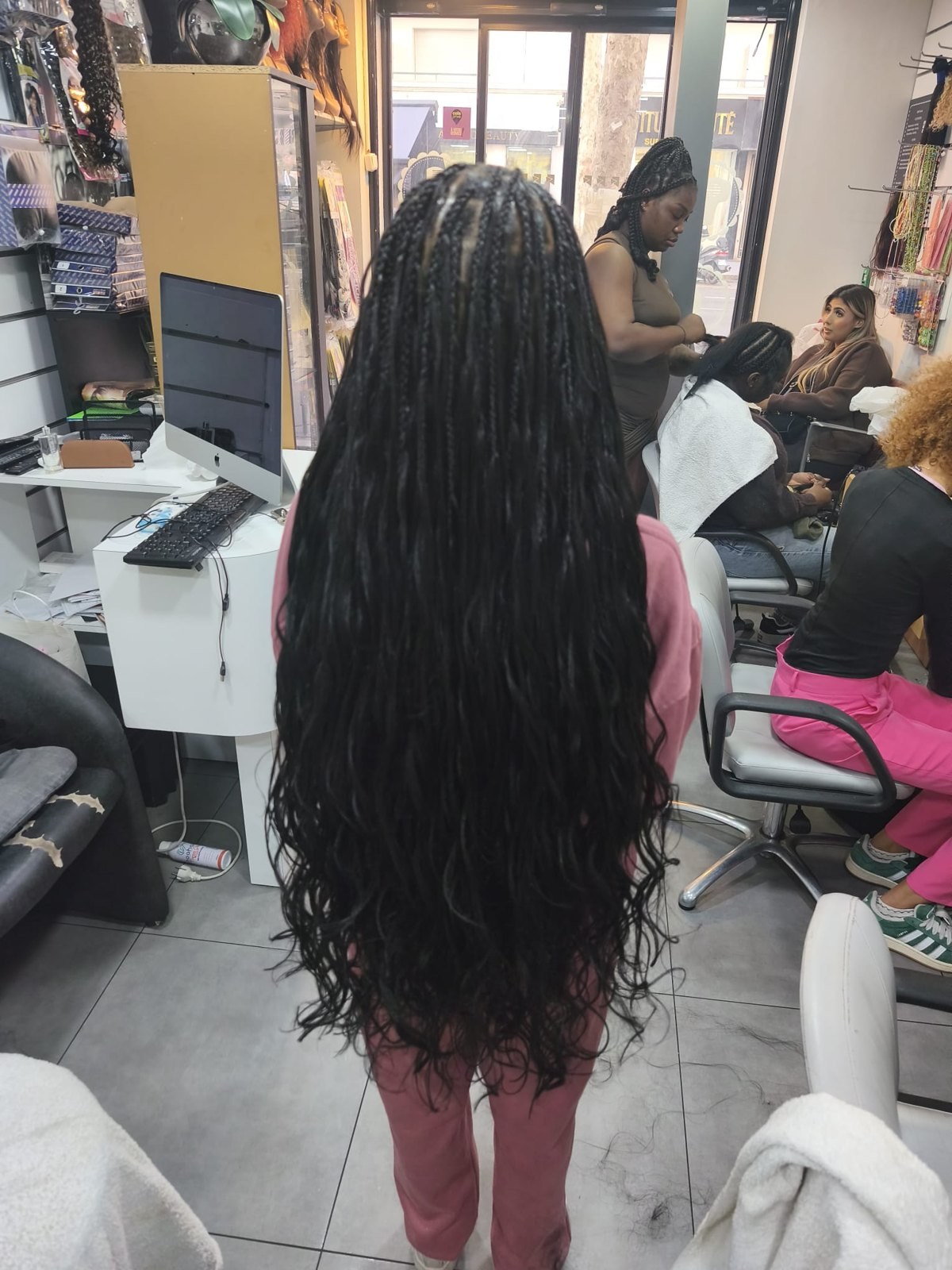 Longues tresses noires aux longueurs bouclées, vues de dos au salon.