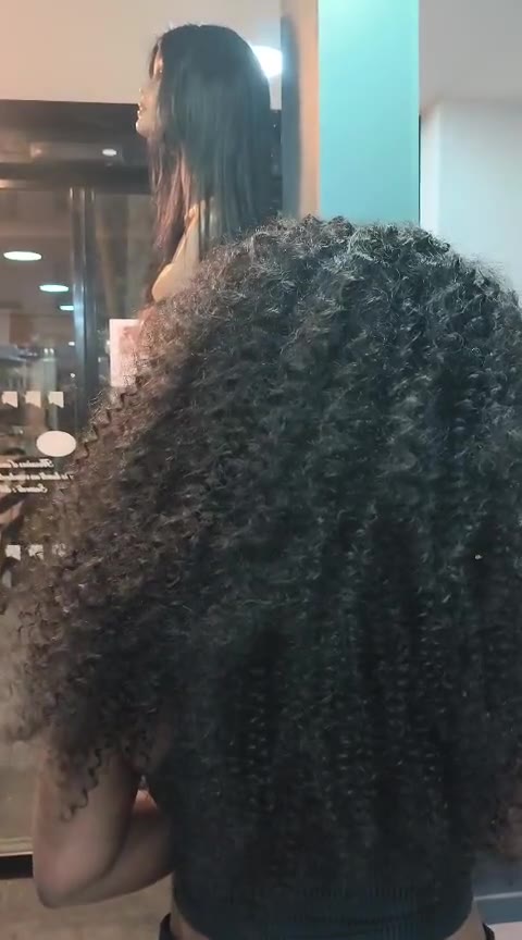 Tissage noir aux boucles denses et souples, vu de dos au salon.