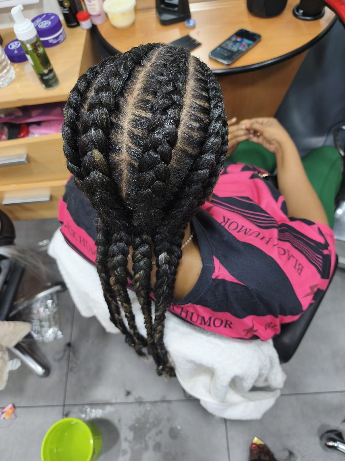 Grosses nattes collées noires avec raies précises et tresses longues, vues de dos.