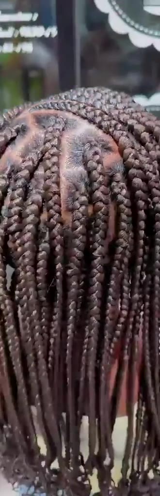 Gros plan sur des tresses brunes aux raies nettes, filmées en mouvement.